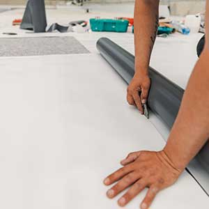 Close up of a worker cutting off a piece from an unrolled single-ply sheet