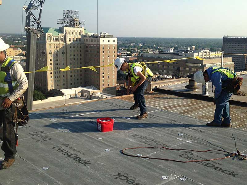 Colonial Roofing of Virginia Inc workers on a roof getting ready to install a new roofing system on a very tall commercial building